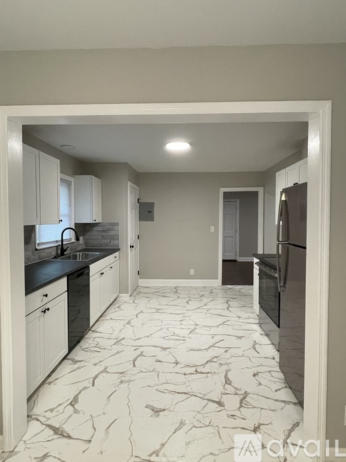 A kitchen with marble flooring and a refrigerator on the right.