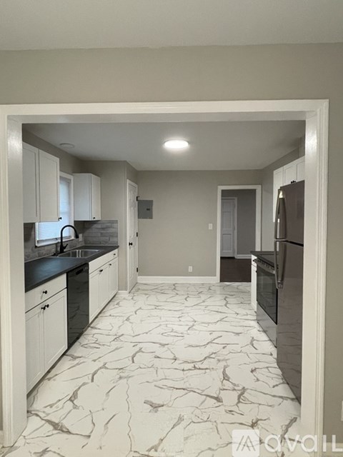 A kitchen with marble flooring and a refrigerator on the right.