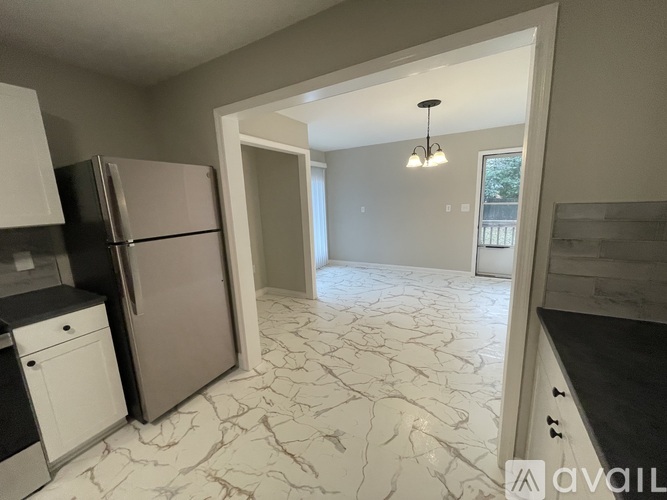 A kitchen with a marble floor and a refrigerator.