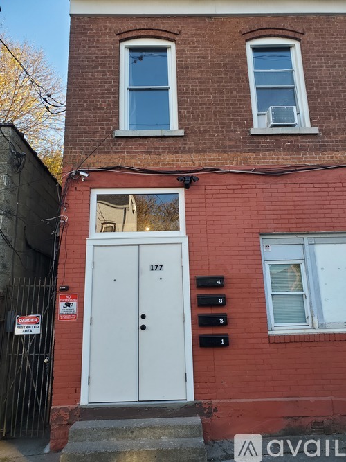 A red brick building with a white door and mailbox number 177.
