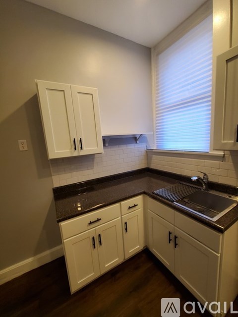 A kitchen with white cabinets and a black countertop.