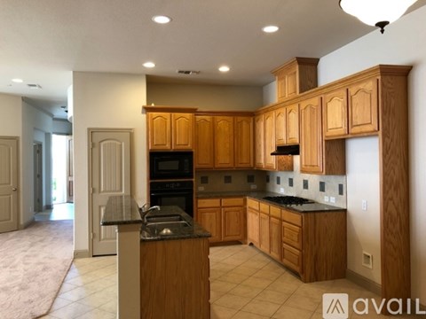 A kitchen with wooden cabinets and a black countertop.