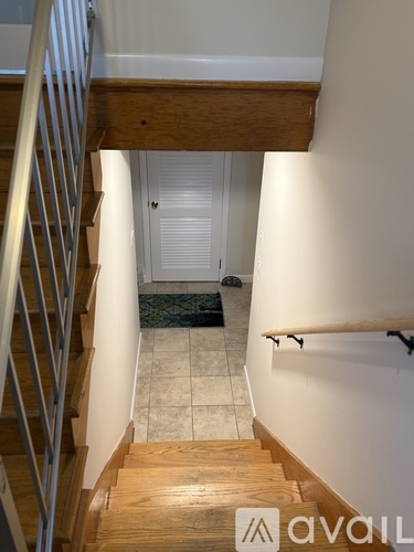A staircase with a metal railing and wooden steps leading to a white door.