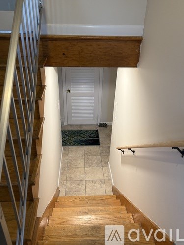 A staircase with a metal railing and wooden steps leading to a white door.