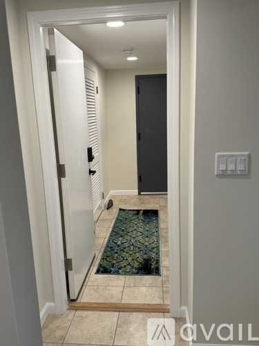 A hallway with a rug on the floor and a door on the left.