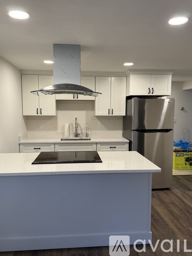 A modern kitchen with white cabinets and a stainless steel refrigerator.