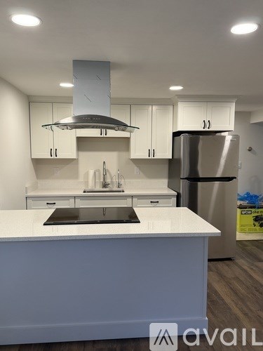 A modern kitchen with white cabinets and a stainless steel refrigerator.