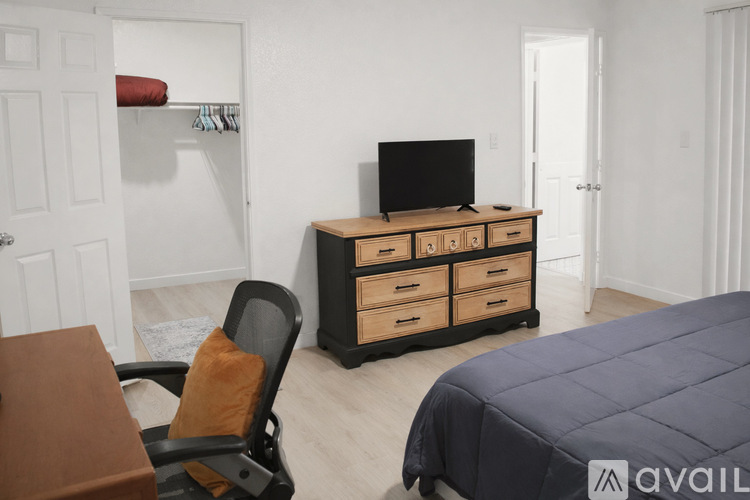 A bedroom with a bed, desk, and TV.