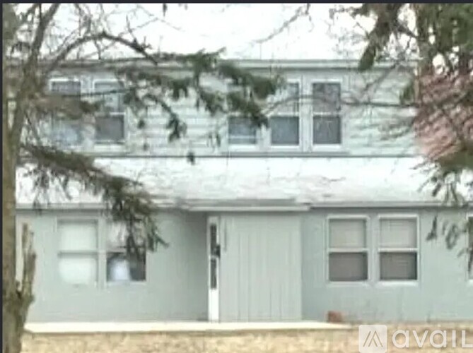 A house with a grey siding and white trim is shown.