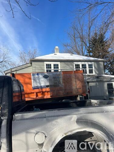 A truck is carrying a large object in front of a house.