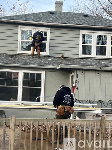A man in a black jacket is standing on a roof.