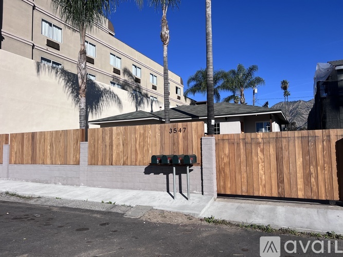 A wooden fence with a mailbox on it in front of a building.