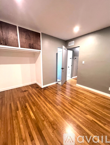 A room with wooden floors and a white wall with a door.