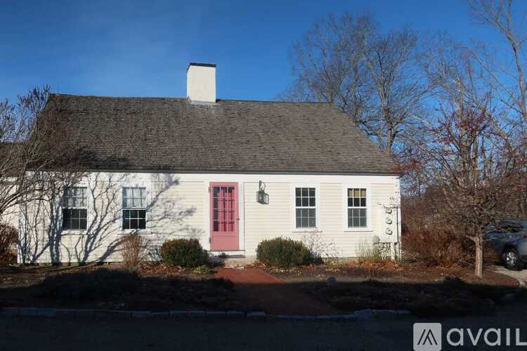 A white house with a red door is surrounded by snow.