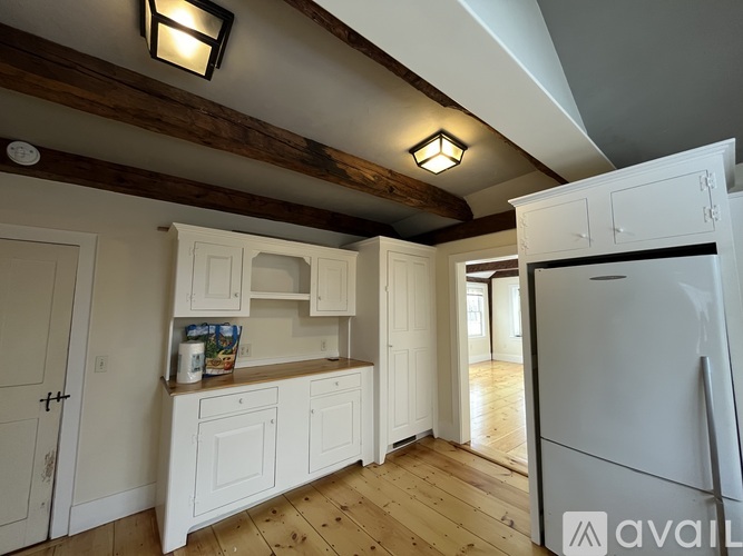 A kitchen with white cabinets and a white refrigerator.