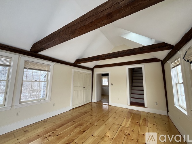 A spacious room with wooden floors and a staircase leading to another room.