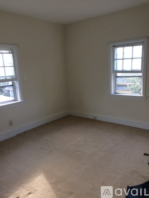 A room with two windows and carpeted floor.