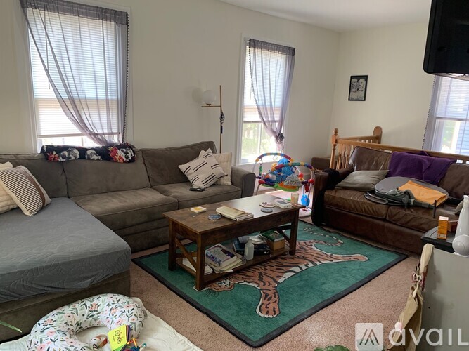 A living room with a grey couch, a brown sofa, a wooden coffee table, and a TV mounted on the wall.