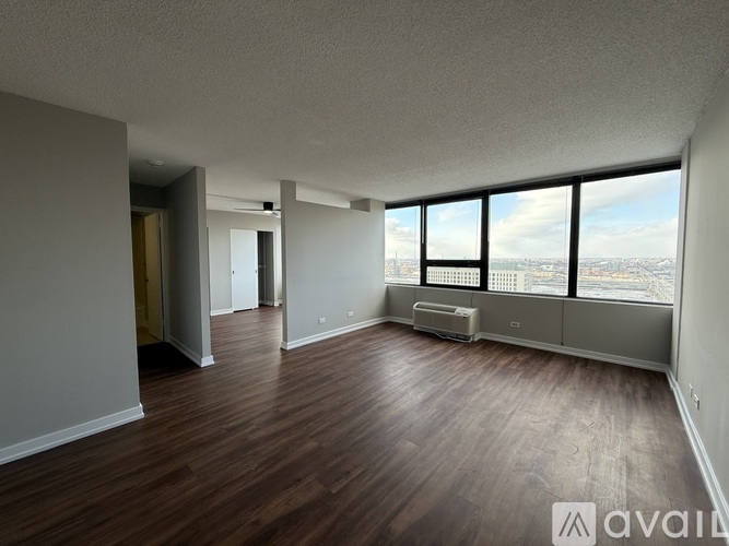 A spacious room with wooden floors and large windows overlooking the city.