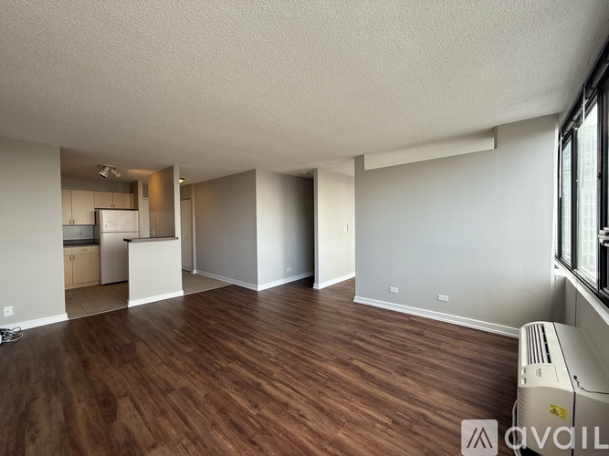 A room with wooden floors and a window on the right side.