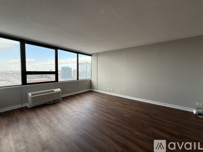 A room with wooden floors and a large window overlooking a cityscape.