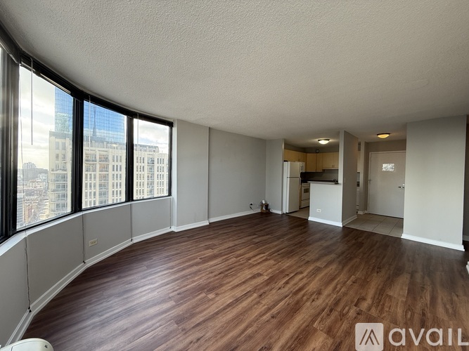 A spacious room with wooden flooring and large windows overlooking a cityscape.