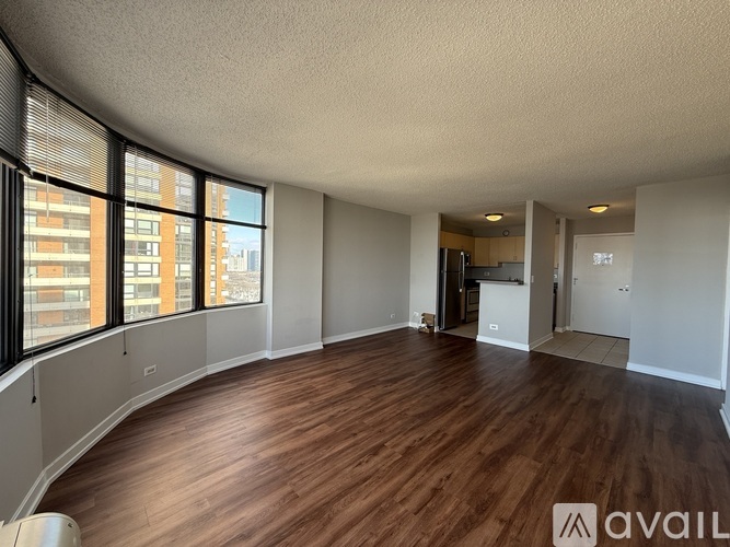 A spacious room with wooden flooring and large windows.