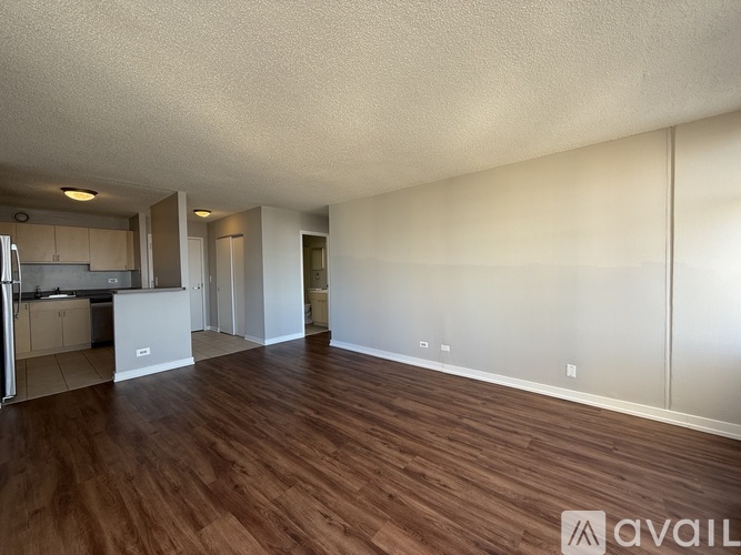 A spacious room with wooden flooring and white walls.