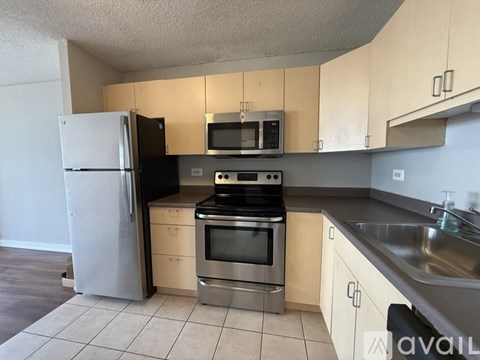 A kitchen with a refrigerator, microwave, oven, and sink.