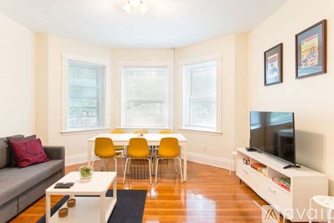 A living room with a grey couch, yellow chairs, a white coffee table, and a television on a white stand.