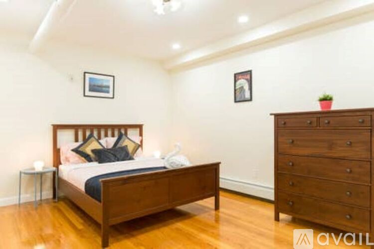 A bedroom with a bed, nightstand, and dresser.
