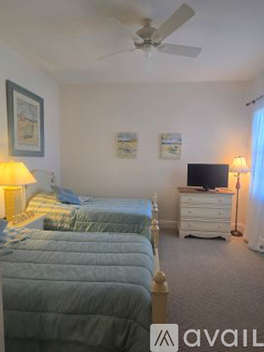 A bedroom with two beds and a television.