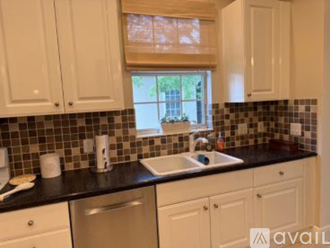 A kitchen with white cabinets and a black countertop.