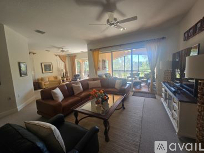A living room with a brown couch and a ceiling fan.
