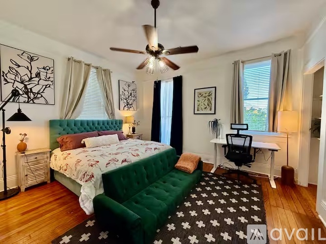 A bedroom with a green bed and a ceiling fan.