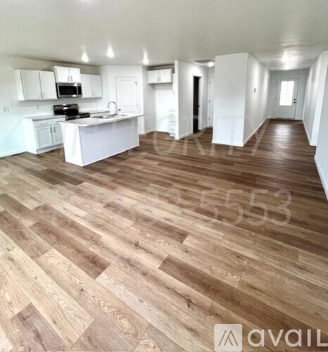 A spacious room with wooden flooring and white walls.