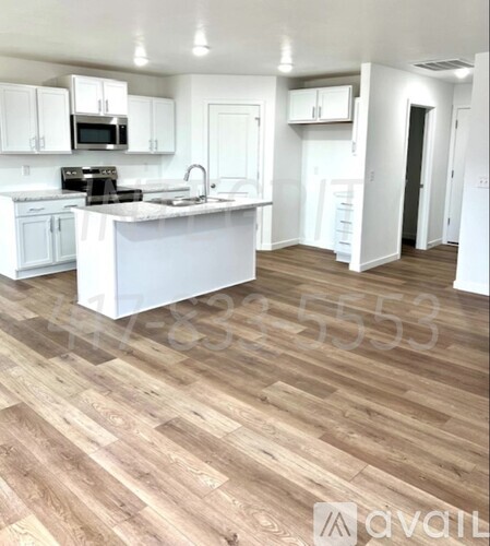 A kitchen with white cabinets and a wooden floor.
