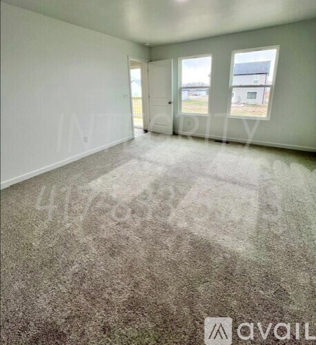 A room with a carpeted floor and a window showing a view of a building outside.