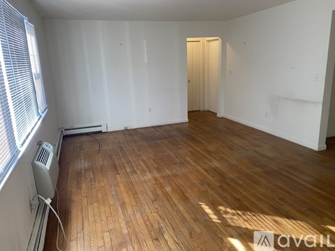 A room with wooden flooring and a window with blinds.