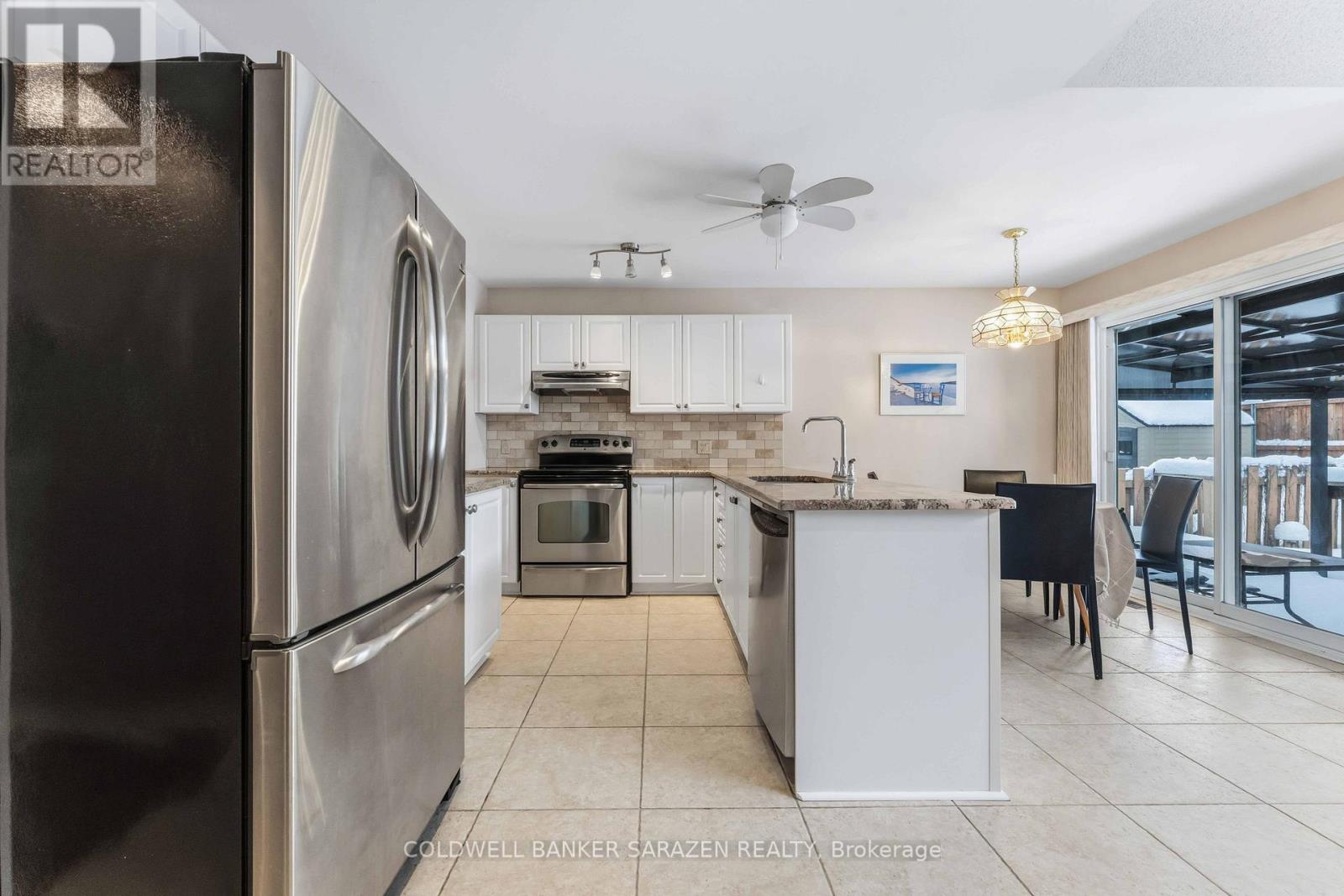 A modern kitchen with a refrigerator, microwave, oven, and a dining table set up.