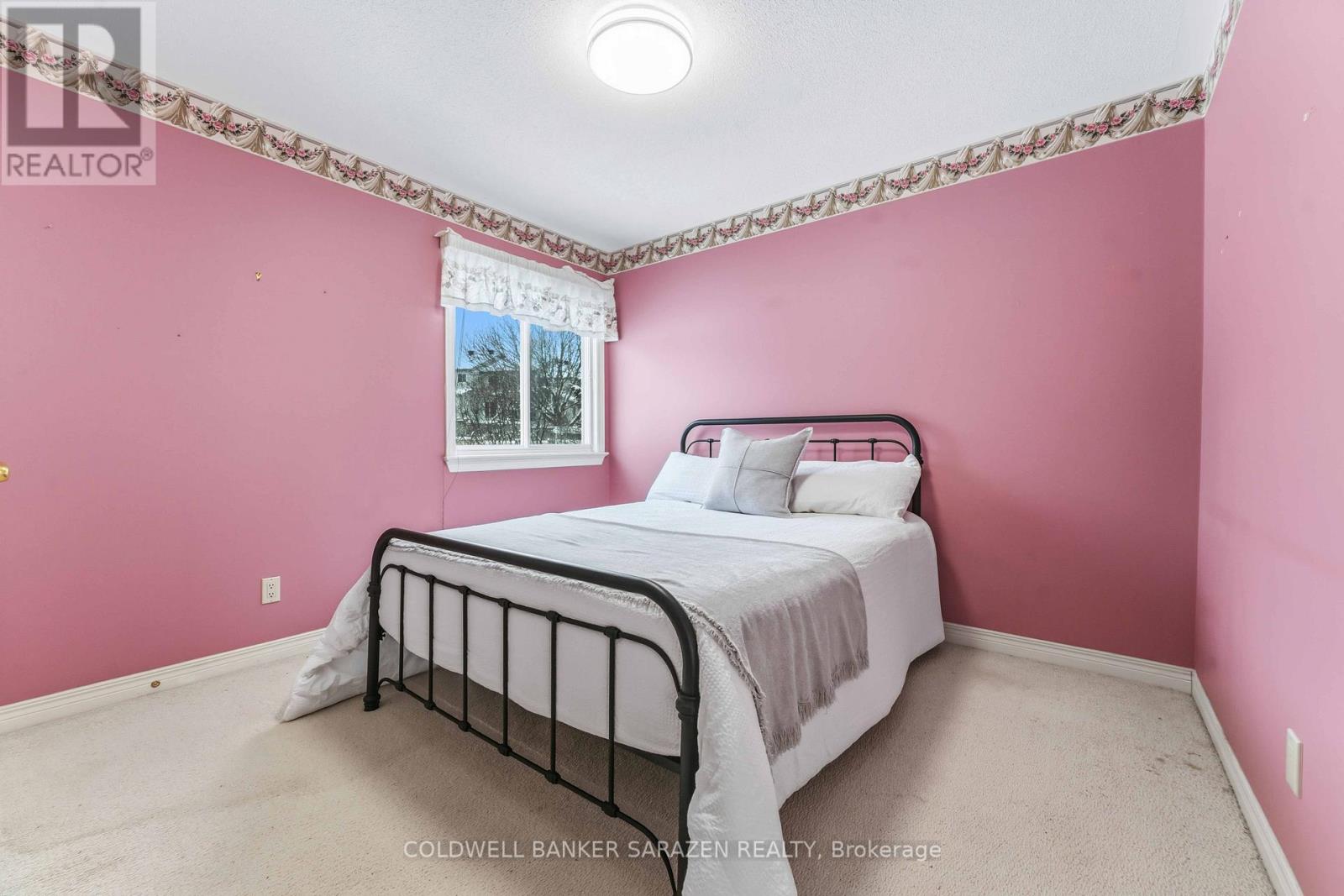 A bedroom with pink walls and a bed with a white comforter.