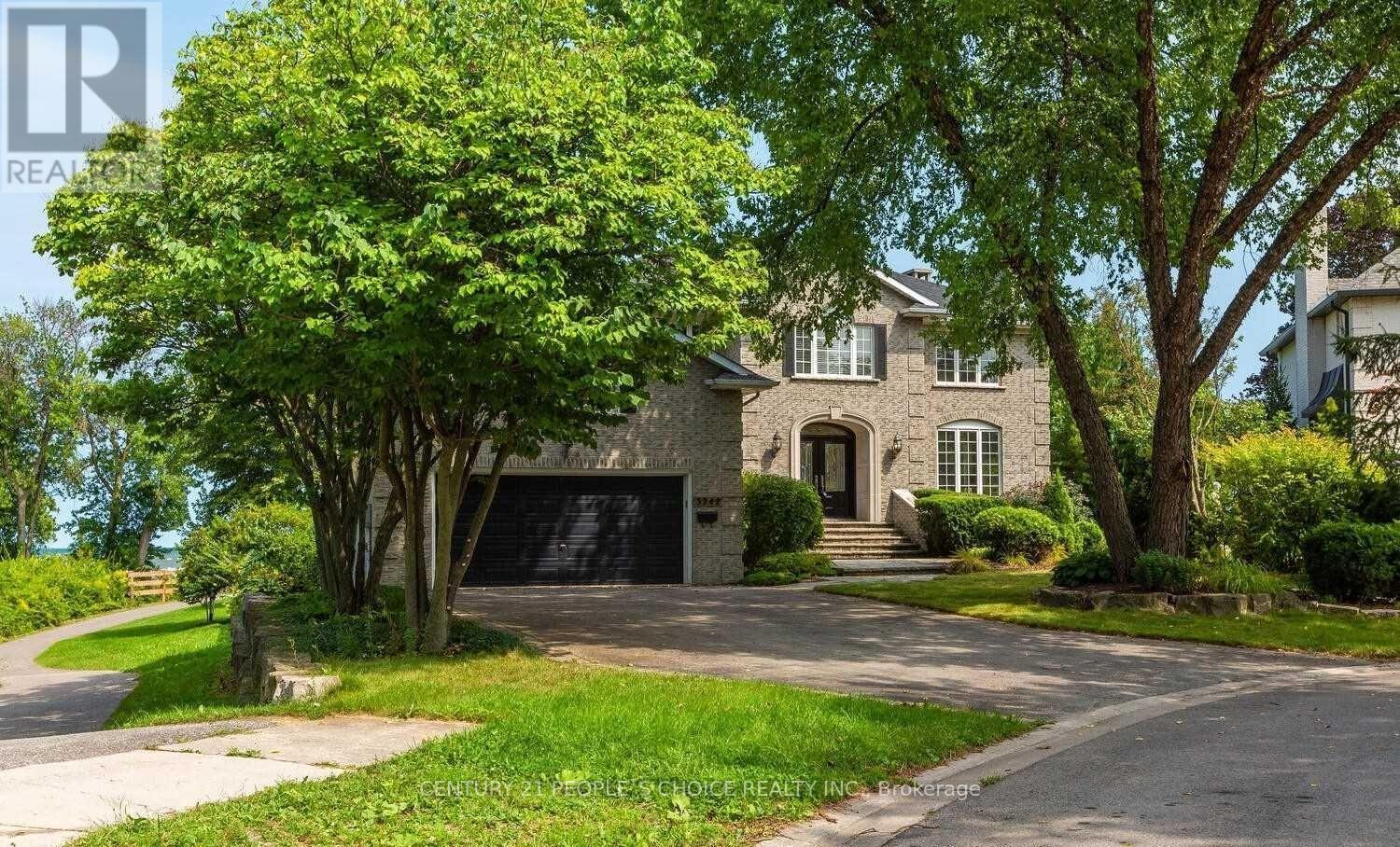 A large house with a driveway and trees in front.