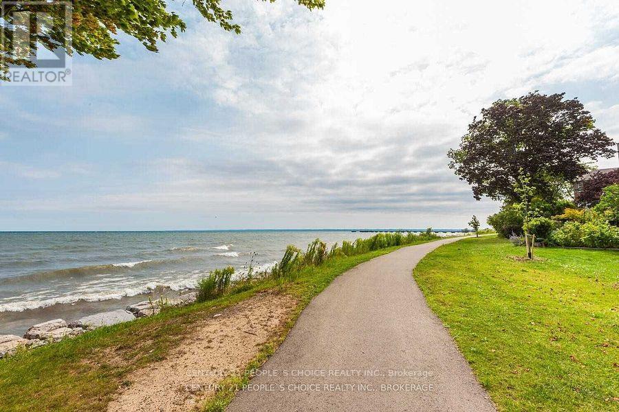 A pathway leads down to a beach with a sign for a realtor in the foreground.