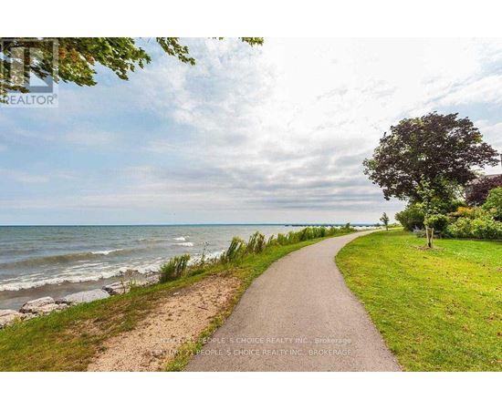 A pathway leads down to a beach with a sign for a realtor in the foreground.