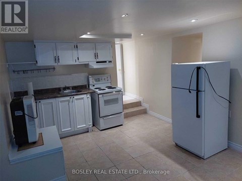 A kitchen with a refrigerator, stove, and cabinets.