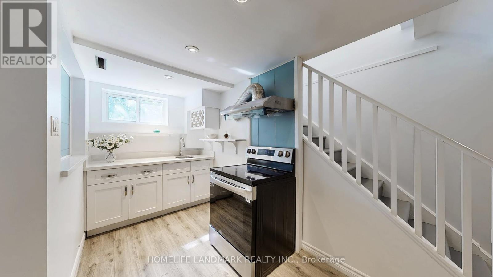 A kitchen with white cabinets and a wooden floor.