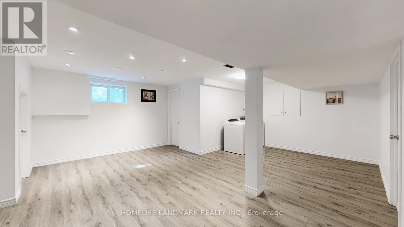 A spacious room with wooden flooring and white walls, featuring a large window and a white radiator.