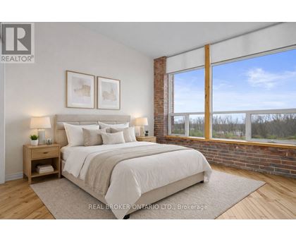 A bedroom with a large bed and a window overlooking a wooded area.
