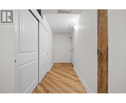 A hallway with wood flooring and white walls.