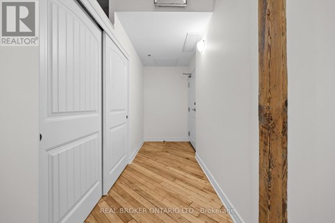 A hallway with wood flooring and white walls.